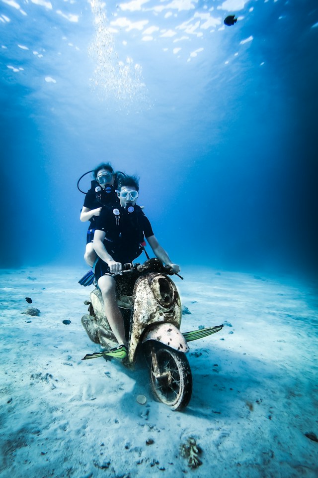 couple on moped underwater with scuba gear