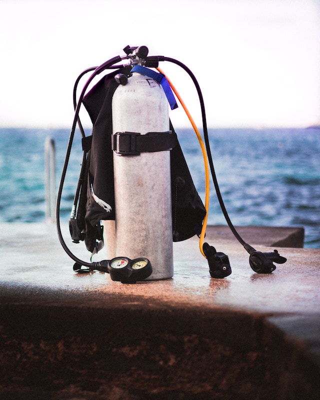 scuba gear gas tank sitting on ledge next to water